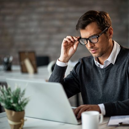 Mann mit Brille im Büro vor Laptop