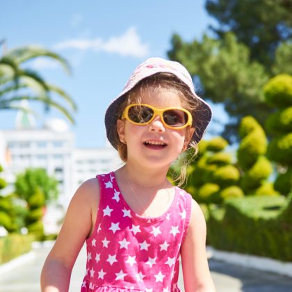 Blondes Kind mit Sonnenhut und Sonnenbrille