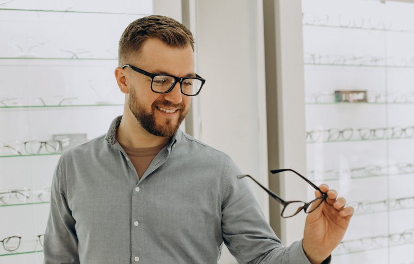 Mann in Optikgeschäft bei Brillenauswahl