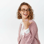 Dunkelblonde, lachende Frau mit Locken und brauner Brille