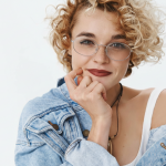 Frau mit blonden Locken und ovaler Metallbrille