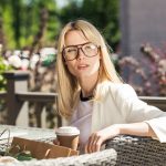 Blonde Frau mit großer Brille in einem Gastgarten