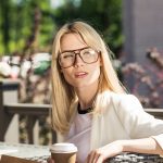 Blonde Frau mit großer Brille in einem Gastgarten