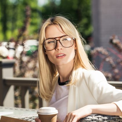 Blonde Frau mit großer Brille in einem Gastgarten