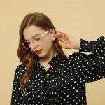 Dunkelhaarige Frau mit geblümter Bluse und Brille