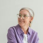 Frau mit grauen Haaren und hellgrüner Brille