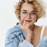Blonde Frau mit Locken und blauer Brille