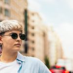 Frau mit lurzen Haaren und Sonnenbrille in einer Stadt