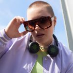 Junge Frau mit kurzen Haaren und großer Sonnenbrille