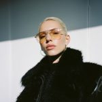 Frau mit blonden Haaren, schwarzer Jacke und großer Retro-Sonnenbrille