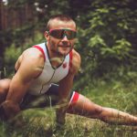 Mann im Wald beim Dehnen mit Sport-Outfit und Sonnenbrille