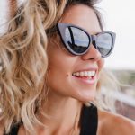 Close-up von blonder, lächelnder Frau mit schwarzer Sonnenbrille