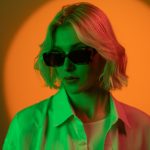 Blonde Frau mit Sonnenbrille in orange beleuchtetem Hintergrund