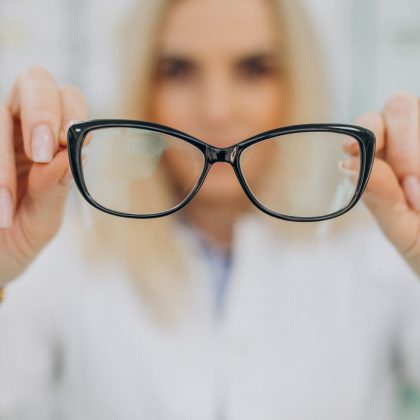 Frau hält Brille in die Kamera