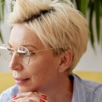Frau mit blonden kurzen Haaren und goldener Metallbrille