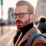 Dunkelhaariger Mann mit Rollkragenpullover und schwarzer Brille